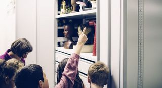 Eine Gruppe von Kindern im Sammlungsdepot vor einem offenen Depotschrank