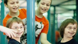 Ein Mädchen mit Down-Syndrom im Spiegelkabinett des Kinder-Museums
