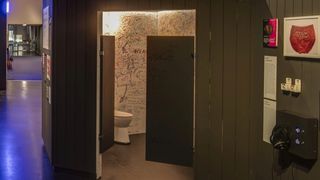 Eine Toilette mit Wänden, an denen sich die Besucher verewigen können. Rechts von der Tür eine Hörstation unterhalb einer gerahmten Unterhose.