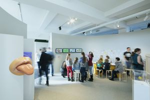 Erwachsene und Kinder an Kreativtischen im Kinder-Museum. Im Vordergrund ein großes Zungen-Modell.