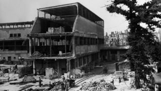 Eine Schwarzweiß-Aufnahme, die den Nordflügel des Museums nach der Zerstörung durch Bombenangriffe während des Zweiten Weltkrieges zeigt. Etwa die Hälfte des Gebäudeteils ist durch den Einschlag weggerissen. Helfer türmen die Trümmer auf Haufen.