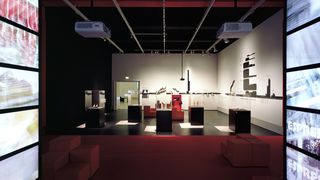 Ein dunkler Ausstellungsraum, in dessen Mitte fünf Vitrinen mit Exponaten stehen.