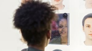 Mladá žena před zrcadlem u stanoviště ideálů krásy. Vlevo i vpravo od zrcadla jsou uspořádány různé podobizny.