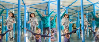Drei Mädchen jubeln und hüpfen im Spiegelkabinett des Kinder-Museums