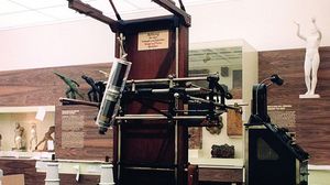 Historischer großer, brauner Röntgenapparat in der Dauerausstellung. Im Hintergrund Wände mit Holzoberflächen und Vitrinen mit alten Statuen.