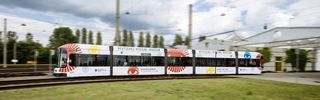 Eine Straßenbahn fährt durch das Bild, auf der Werbung des Hygiene-Museums steht.