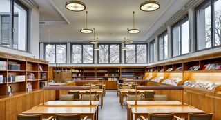 Die Bibliothek des Hygiene-Museums. Im Zentrum des Raums sind Tische aus Holz, Lampen und  Stühle mit Lederbezug. An den Wänden stehen Holzregale mit Büchern und Zeitschriften.