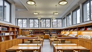 Die Bibliothek des Hygiene-Museums. Im Zentrum des Raums sind Tische aus Holz, Lampen und  Stühle mit Lederbezug. An den Wänden stehen Holzregale mit Büchern und Zeitschriften.