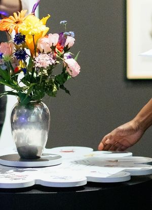 Eine Hand dreht am Blumenglücksrad in der Ausstellung.