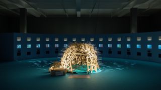 In der Mitte eines dunkelblauen Raumes steht eine runde Hütte aus Holz. Die Außenwände der Hütte sind mit Stacheln versehen.