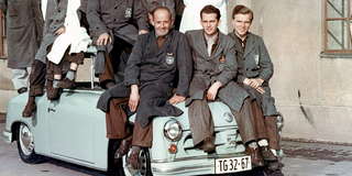 Foto: Acht Ingenieure des VEB Sachsenrings sitzen oder stehen auf einem blauen Trabant, um 1955/60.