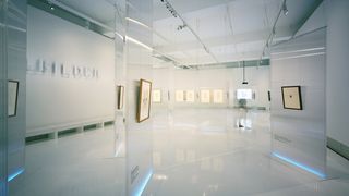 In einem weißen Ausstellungraum zehn Wände aus Milchglas, die unregelmäßig im Raum verteilt sind. An den Wänden hängen Bilder.