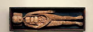 Ein altes Holzmodell einer Schwangeren mit geöffnetem Torsobereich.