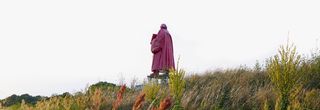 Im Hintergrund ein pink angestrichenes Martin-Luther-Denkmal von hinten in einer Heidelandschaft. Im Vordergrund sind die verschiedenen Pflanzen.
