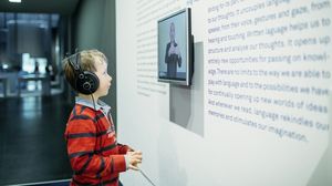 Ein Kind vor einem Objektvideo in Gebärdensprache in der Ausstellung Sprache