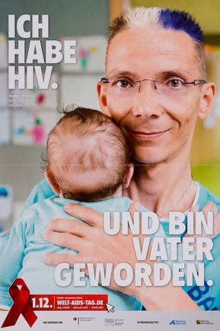 Bild eines Mannes mit bunten Haaren und Brille und seines Babys. Oben links steht in weißen Großbuchstaben &quot;ich habe HIV.&quot; und unten rechts in gelicher Schrift &quot;Und bin Vater geworden.&quot;