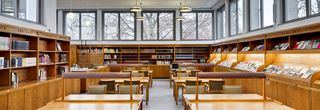 Die Bibliothek des Hygiene-Museums. Im Zentrum des Raums sind Tische aus Holz, Lampen und  Stühle mit Lederbezug. An den Wänden stehen Holzregale mit Büchern und Zeitschriften.