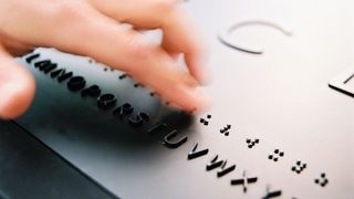 Ein Finger fährt über Braille-Schrift, die sich in der Dauerausstellung befindet.