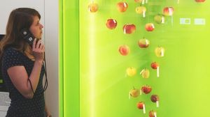 Mladá žena s audioprůvodcem před vitrínou s odrůdami jablek pěstovanými v Německu.